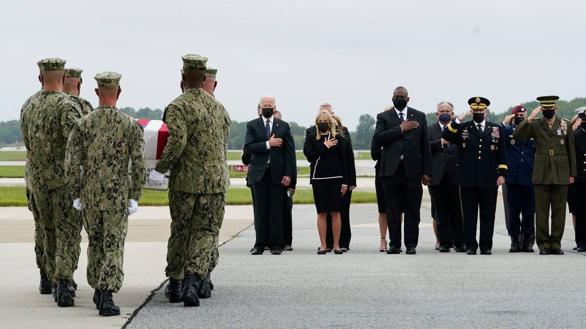 President Joe Biden watches as a Navy carry team moves a transfer case containing the remains...